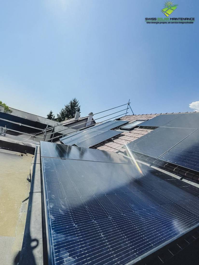 Champ de panneaux solaires installé sur une toiture en tuiles avec fenêtre de toit sous ciel bleu