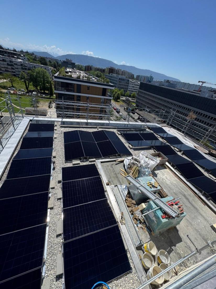 Vue aérienne d'une installation de panneaux solaires sur toit plat d'immeuble en chantier à Genève