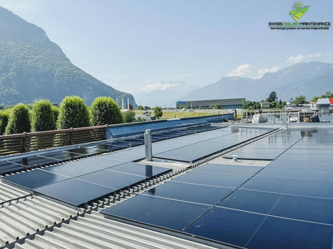 Panneaux solaires sur toiture plate en tôle d'un bâtiment avec les Alpes suisses en arrière-plan