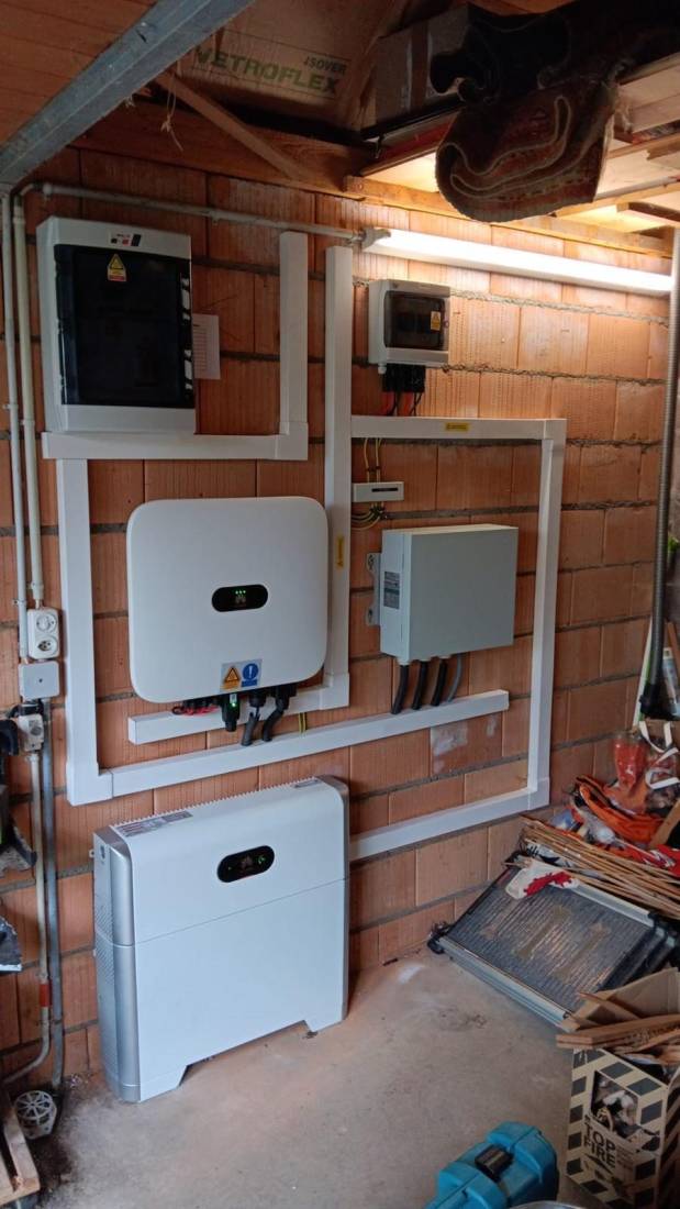 Onduleur solaire, batterie de stockage et coffrets électriques montés au mur d'un local technique à Genève