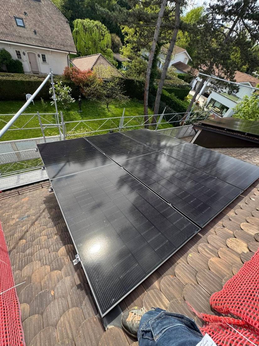 Panneaux solaires full black posés sur une toiture en tuiles dans un quartier résidentiel suisse arboré
